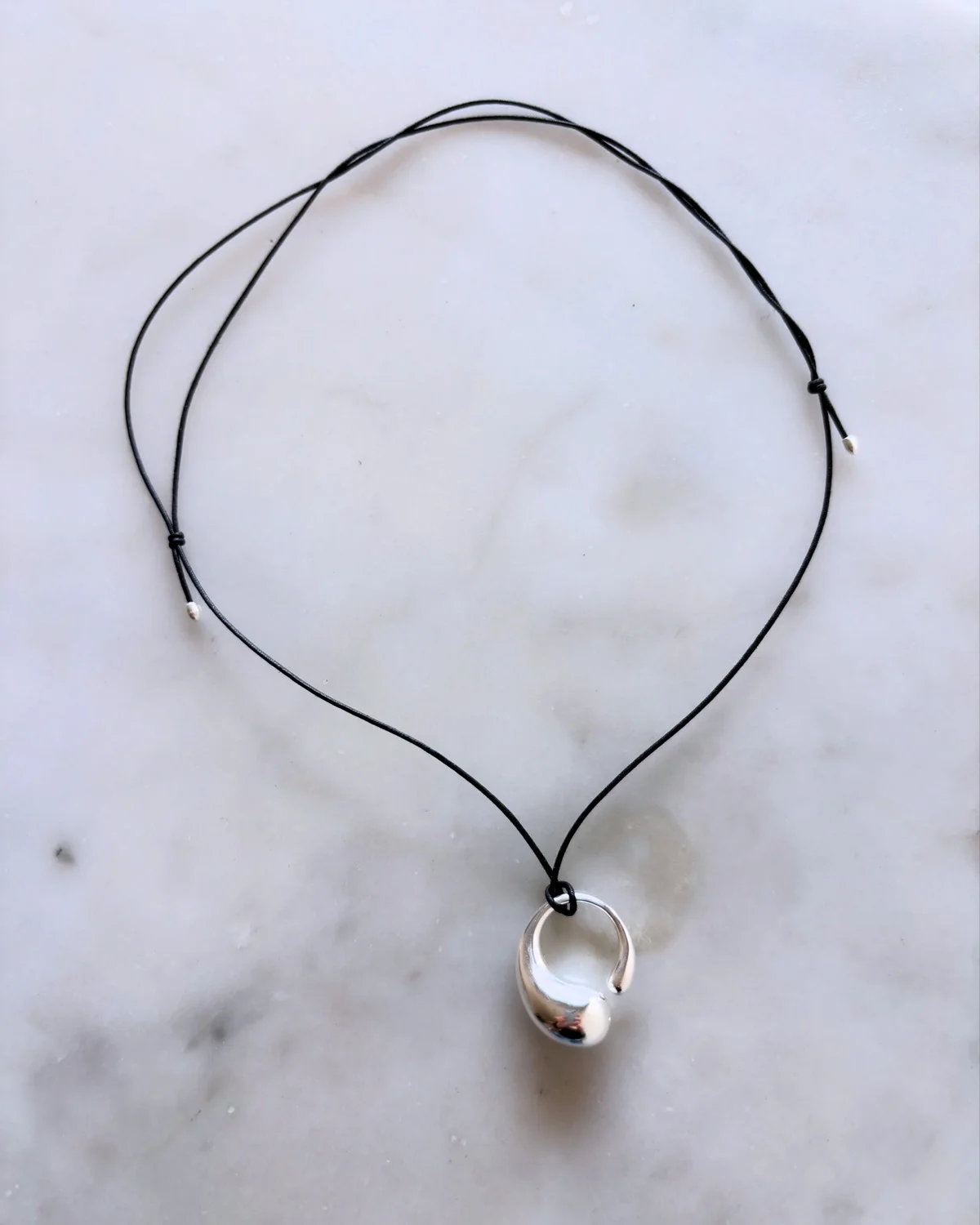 ジョージ ジェンセンの新作 「マーシー」ペンダント（M）。黒いコットンコードは長さを自在に調整できる