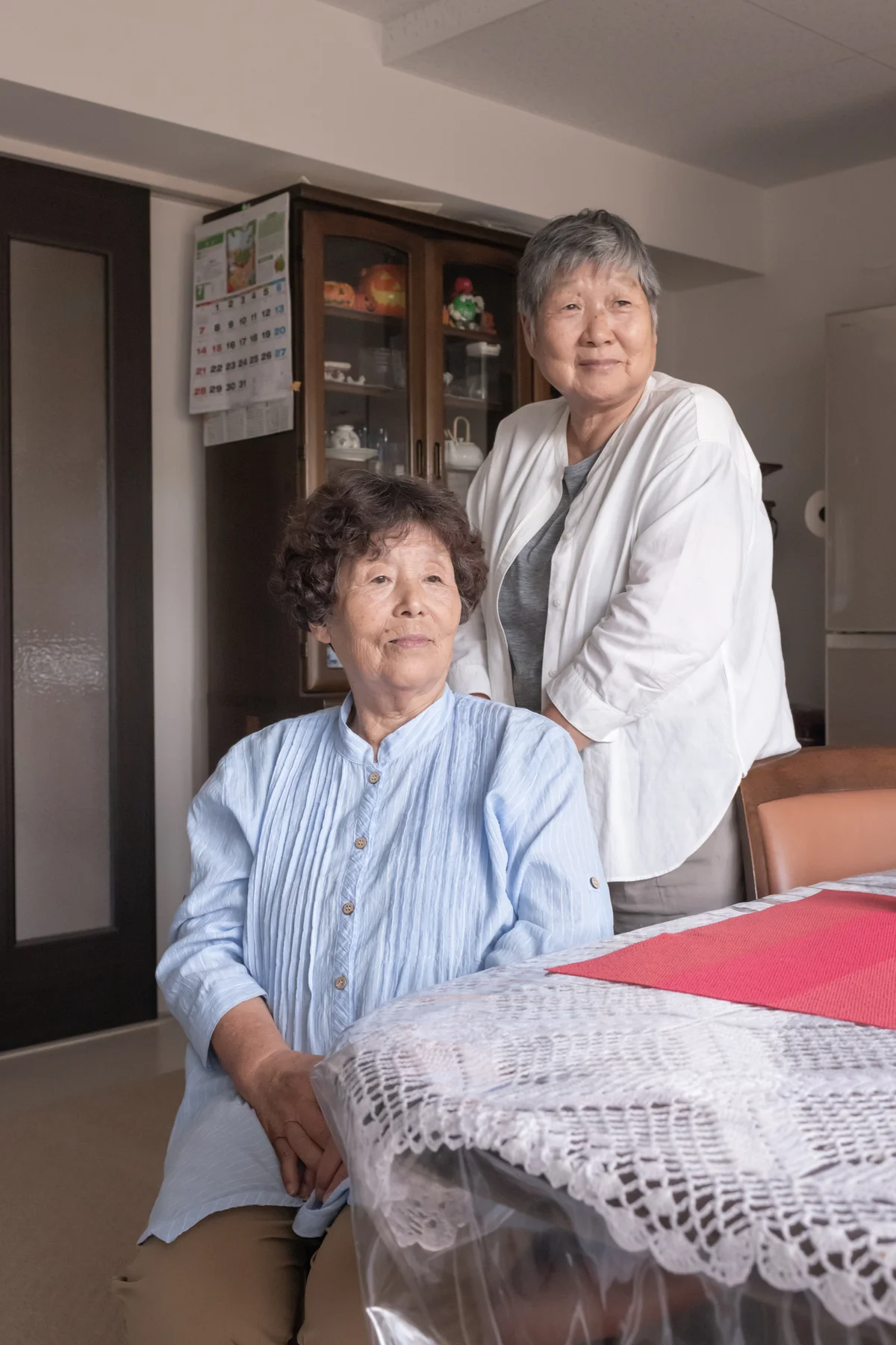 市営住宅の部屋から窓の外を眺める、金真木子さん、真知子さん姉妹。