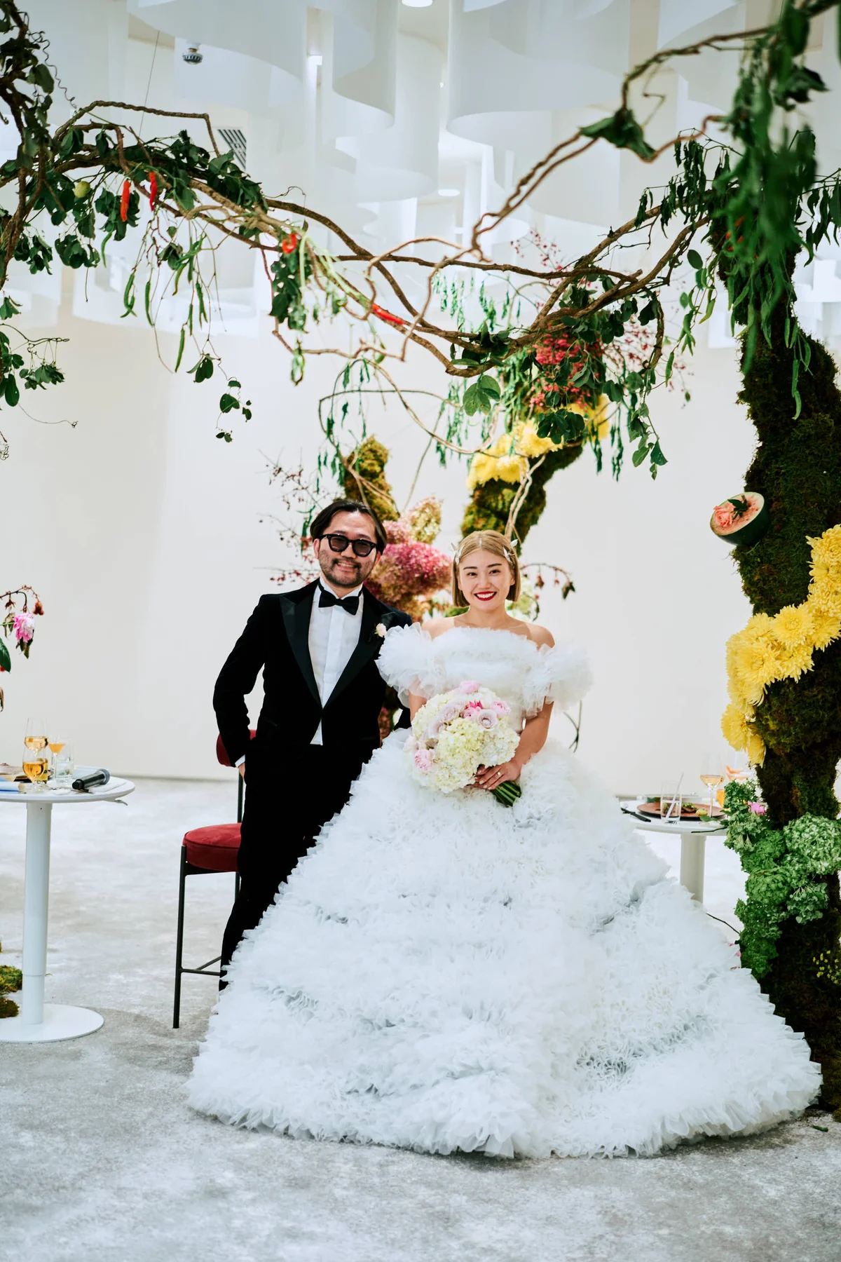 TOMO KOIZUMIを象徴するフリルが際立つドレス。織物の艶が美しいビスチェに呼応するよう、紫陽花を軸に薔薇と濃いピンクのトルコ桔梗を束ねた、立体感のあるブーケを合わせて。