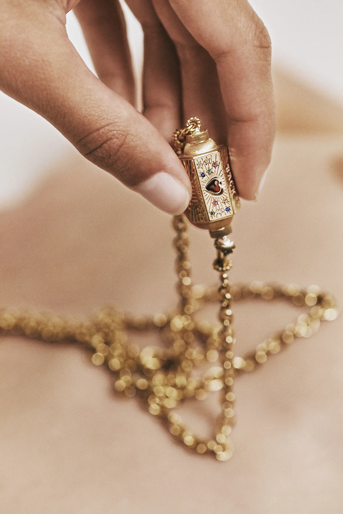 「ラブロケット」ペンダント〈YG、ガーネット、ムーンストーン〉¥770,000、「ローザ クラシック」チェーン〈YG〉¥1,100,000