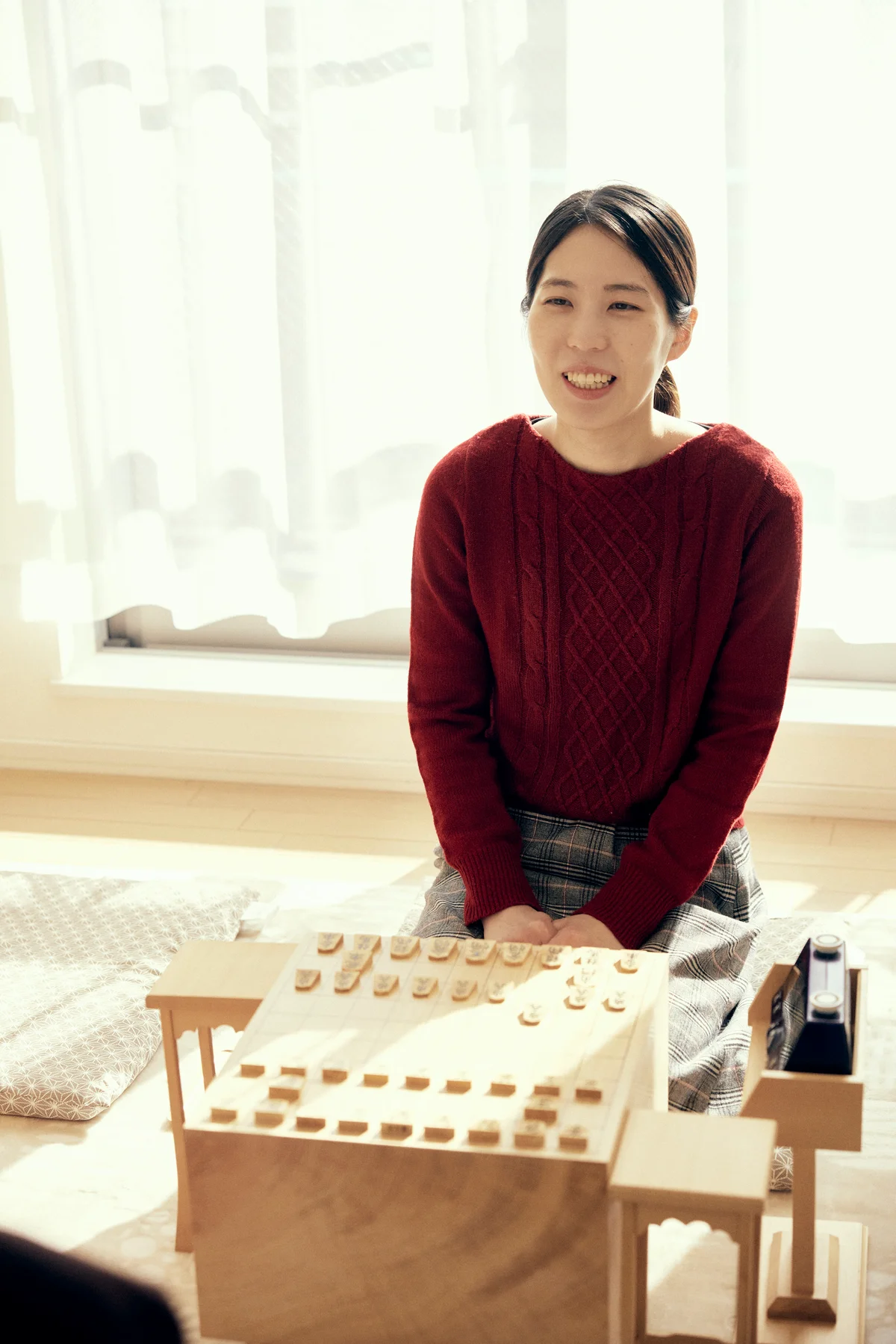 将棋盤の前に座って微笑む福間香奈女流棋士