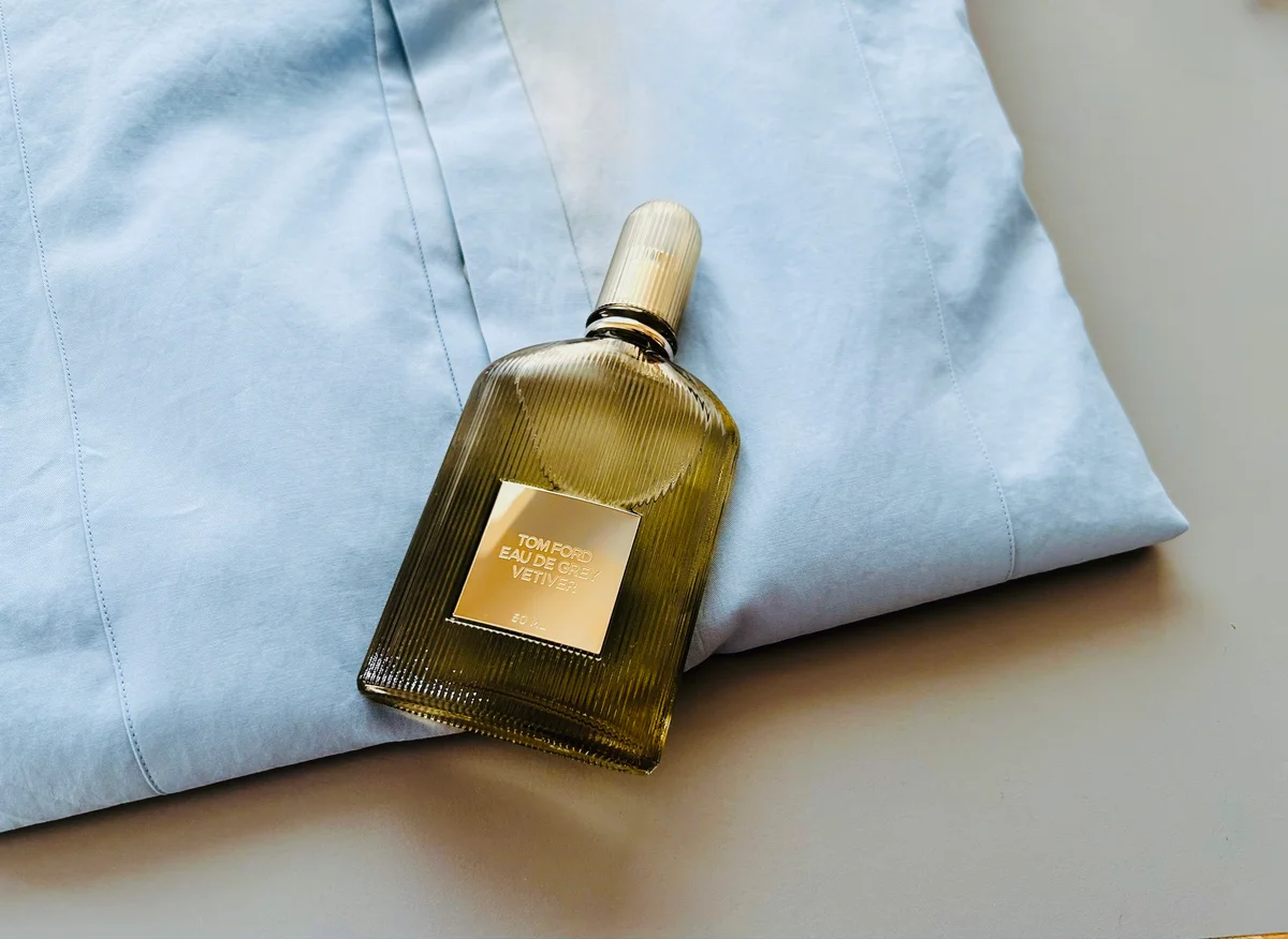 トム フォード グレイ ベチバー オード パルファム スプレィのボトルと水色のシャツ