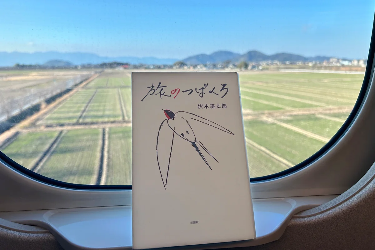 新幹線の座席の窓際に『旅のつばくろ』をたてかけた写真