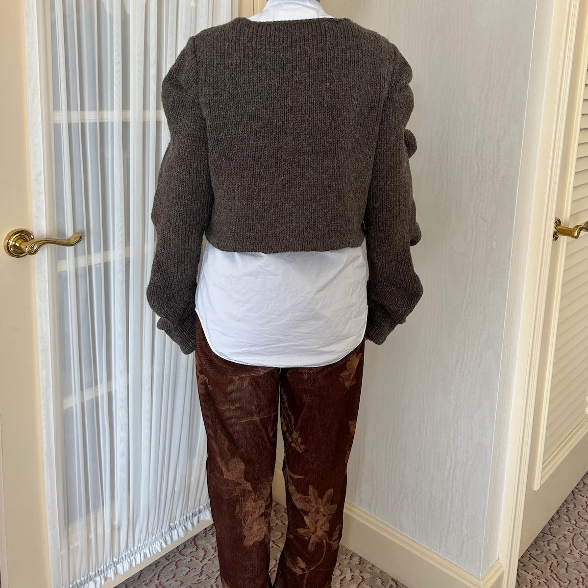 ピリングスのカーディガンSPURSHOP別注のブラウンを着用した後ろ姿