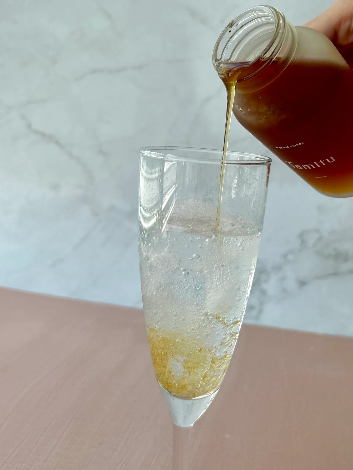 Tamituのハーバルハニーをグラスに注いでいる写真