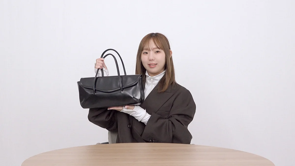 エディターIWASEがコム デ ギャルソン青山店限定のレザーバッグを持っているところ