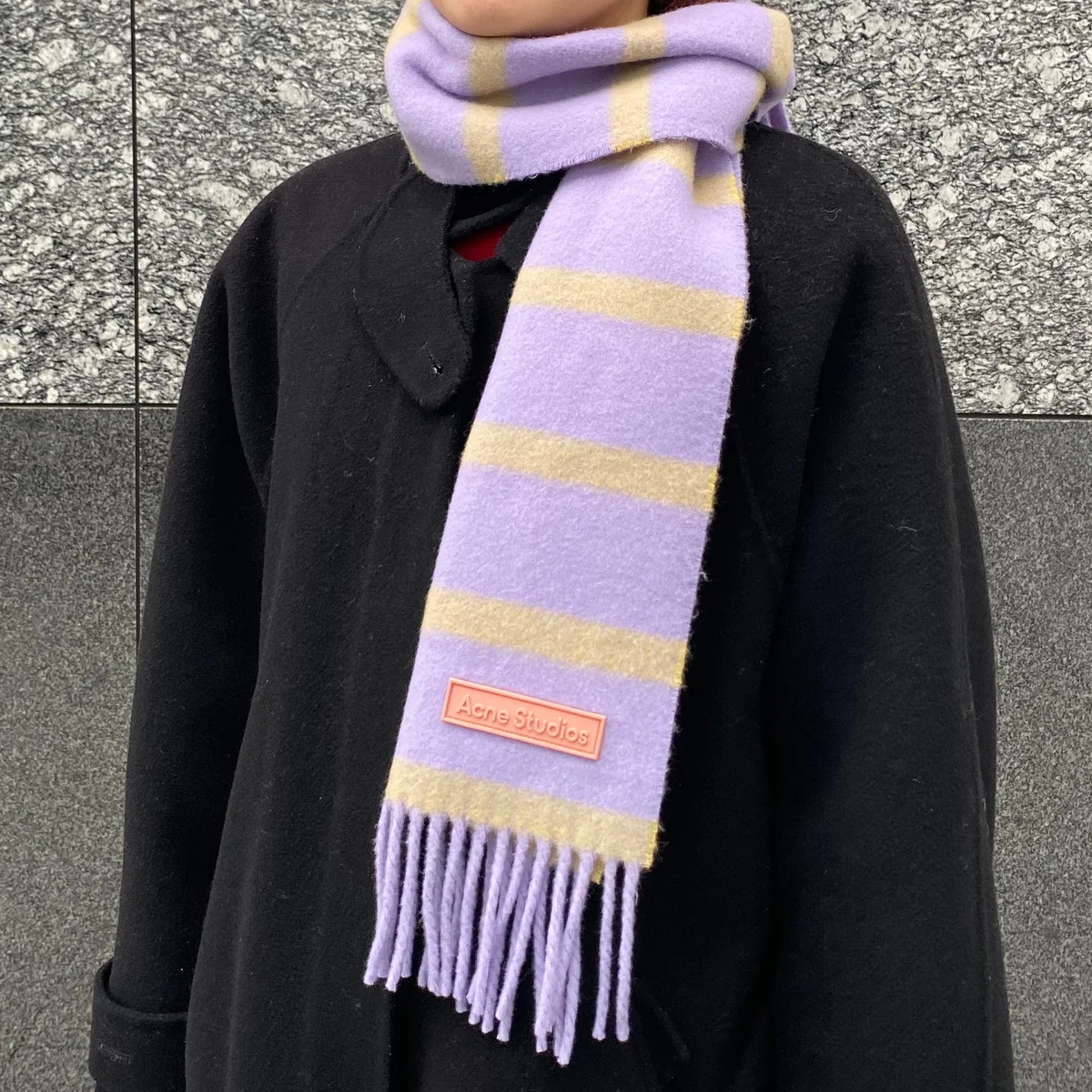 【アクネ ストゥディオズ】の細めマフラーが、黒ロングコートの差し色として活躍中