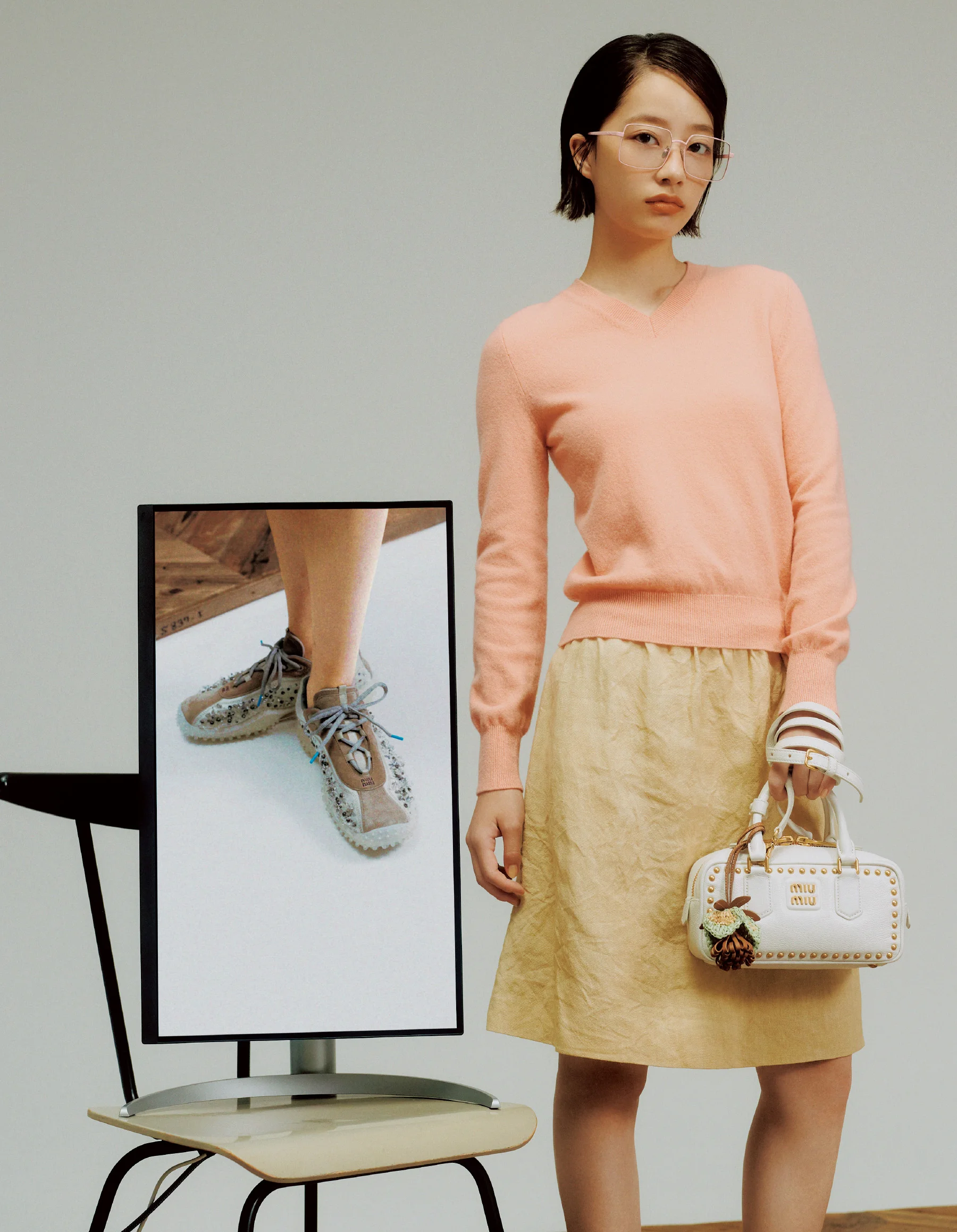 ニット￥214,500・スカート￥253,000・アイウェア￥67,100・バッグ「アルカディ」￥649,000・チャーム￥74,800・スニーカー￥338,800（すべて予定価格）／ミュウミュウ クライアントサービス（ミュウミュウ）